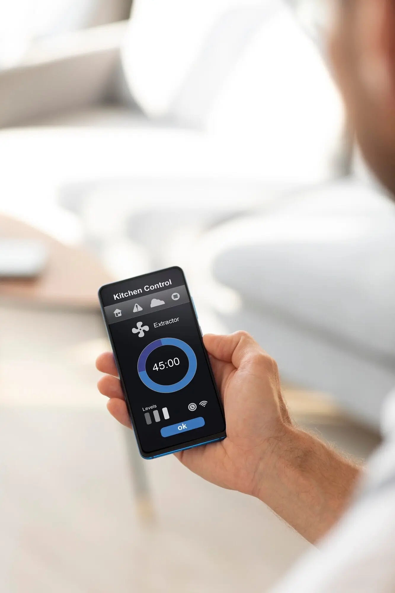 Ein Mann hält ein Smartphone mit einer App zur Hausautomatisierung.